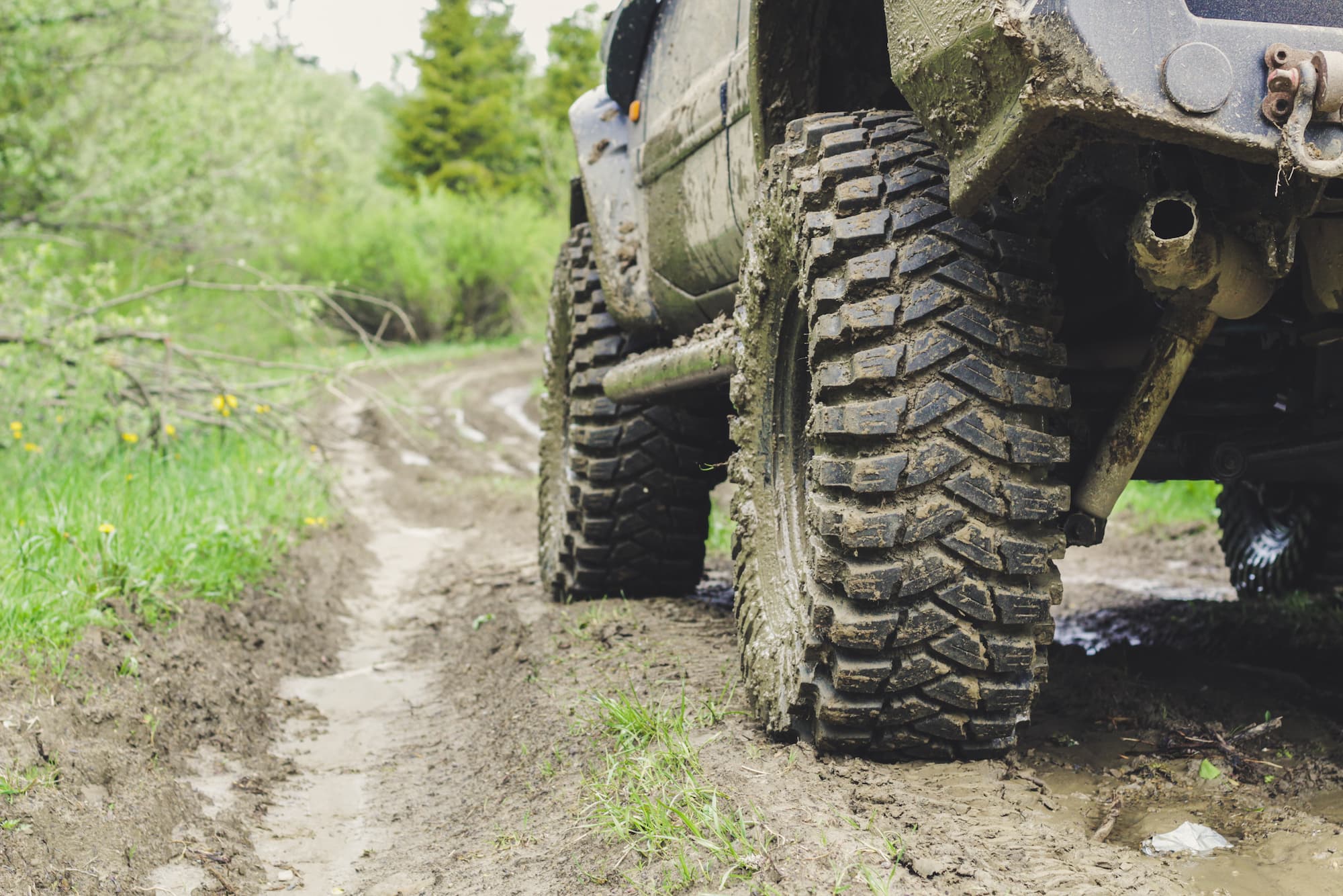 Close-up of mud-covered off-road tires on a Toyota 4Runner navigating a muddy trail