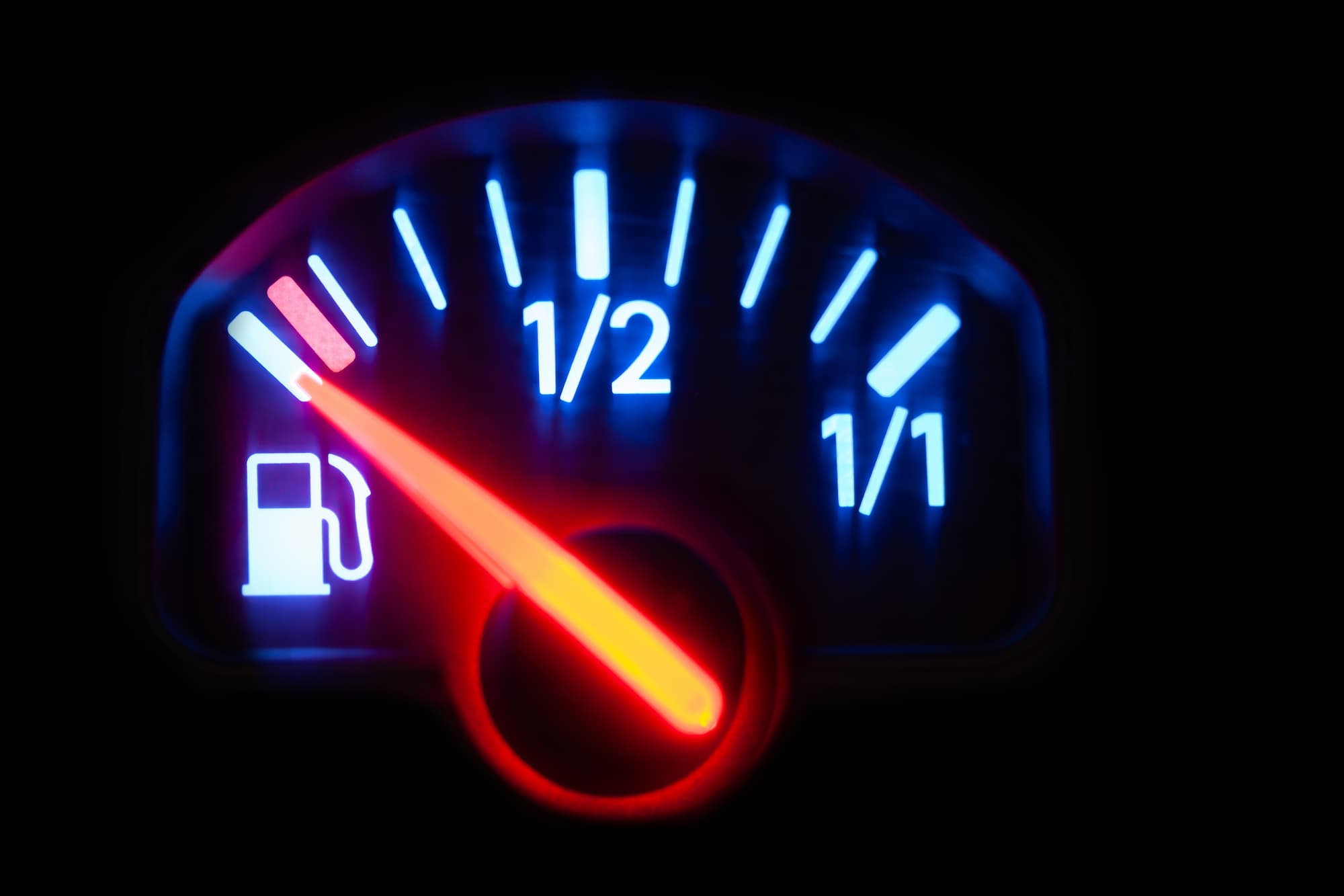 Illuminated car fuel gauge with the needle near empty, representing fuel economy and real-world MPG